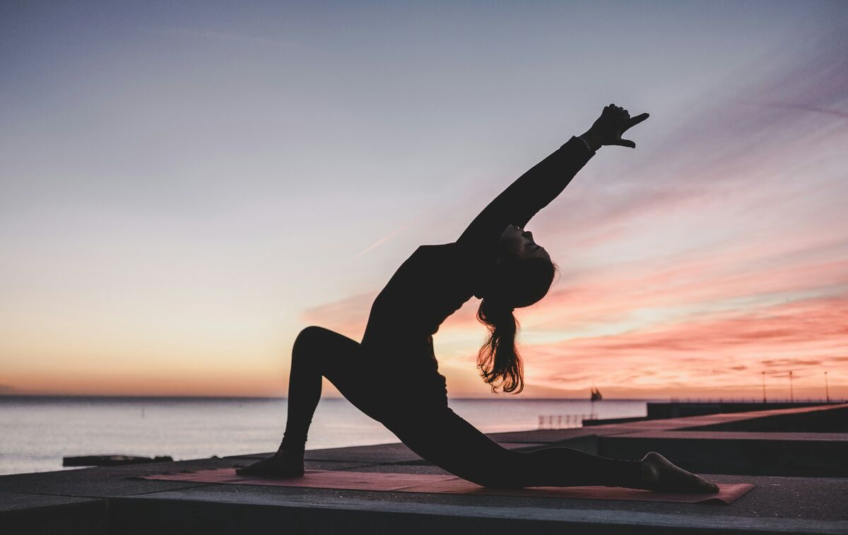 Personne pratiquant le yoga au lever du soleil